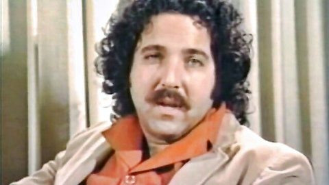 Vintage adult film star with curly hair and mustache in classic MMF scene thumbnail