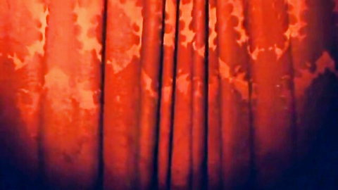 Dramatic close-up of textured red velvet stage curtains in warm lighting