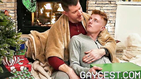 Stepdad embraces redhead stepson in cozy Christmas blanket cuddle
