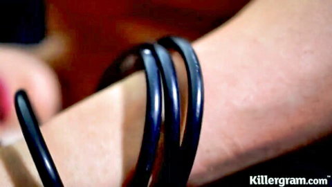 Closeup of fair-skinned woman's wrist with stacked black bangles squeezed tight by manicured hand