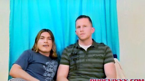 Two smiling young men, one with long hair in blue tee and one in green polo, in gay amateur interview.