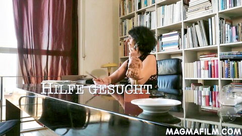 Brunette German babe in black top sits at office desk on phone with 'Hilfe gesucht' text