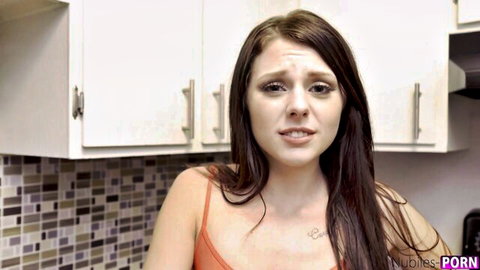 Young brunette teen in tight orange tank top pouting surprised in kitchen