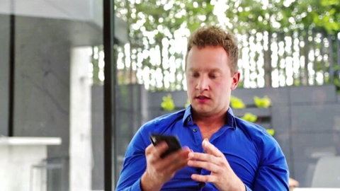 Van Wylde in blue shirt holding phone, teasing Lauren Phillips big boobs video