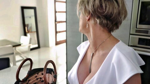 Dee Williams in low-cut white dress, busty blonde MILF showing deep cleavage