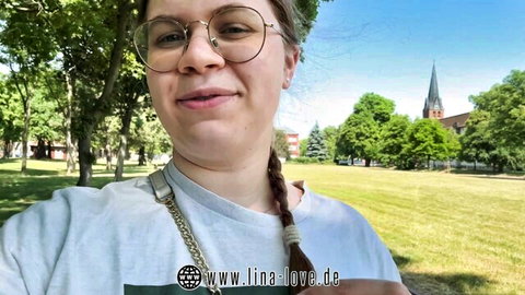 Lina Love smiling outdoors in park, glasses, braided hair, casual top