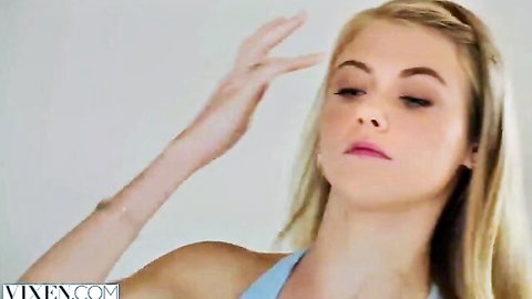 Blonde sissy in blue tank top gesturing playfully in feminization scene