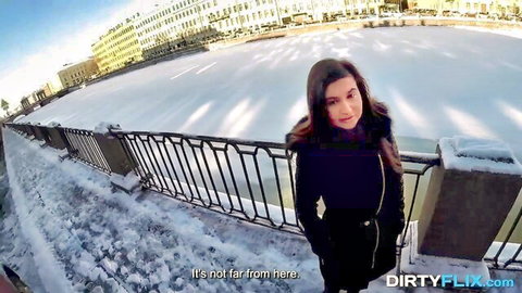 Brunette beauty in black coat on snowy urban bridge, vacation tease