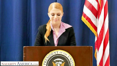 Penny Pax as redhead president in suit at podium, teasing big tits