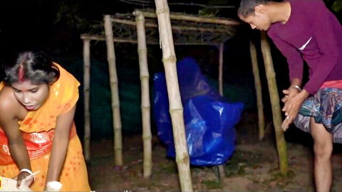 Desi Indian wife in orange saree washes dishes as hubby watches intently outdoors