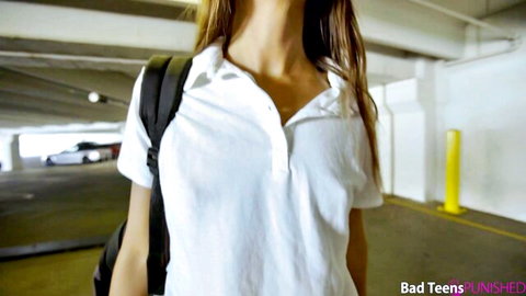 Skinny blonde teen in tight white polo shirt and backpack teasing cleavage in parking garage