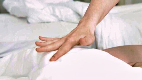 Hand pressing on pregnant woman's body under sheets in rough sex scene