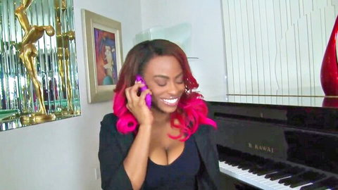 Ebony beauty with huge cleavage smiles on phone call by grand piano