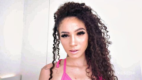 Curly haired Latina babe in pink bra showing deep cleavage and glossy lips