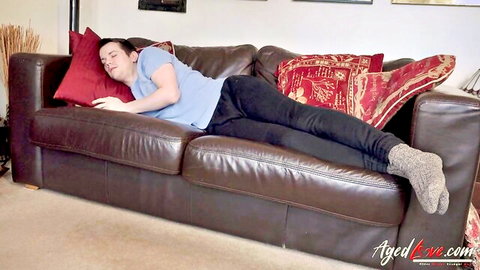 Young twink guy asleep on leather couch in tight black pants and socks