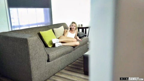 Petite blonde teen in tight white crop top and shorts lounging seductively on couch talking on phone