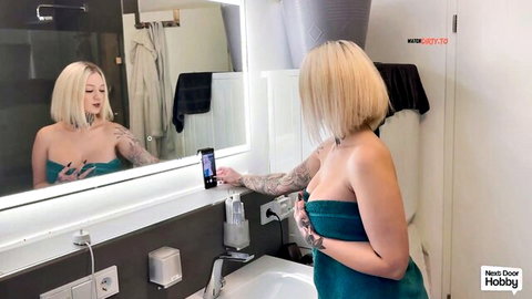 Tattooed blonde babe with big tits and bubble butt in towel takes steamy bathroom mirror selfie