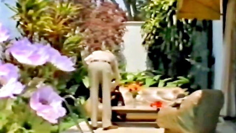 Clothed woman bends over showing tight pants ass in lush outdoor garden patio
