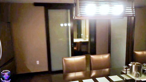Empty modern hotel suite dining room with leather chairs, frosted sliding doors, and table settings.