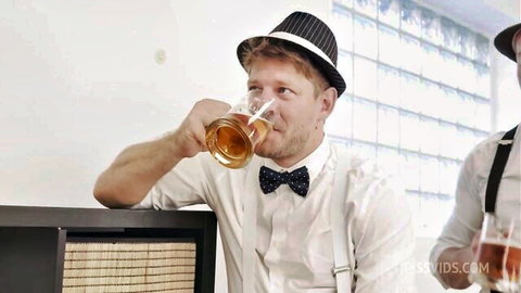 Two stylish men in suits and hats drinking beer at a bar