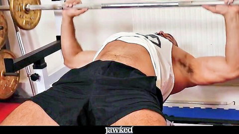 Muscular Portuguese hunk bench pressing in tight gym shorts