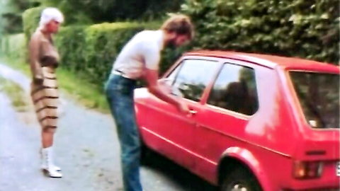 Vintage blonde in striped mini dress teases bearded man unlocking red VW car outdoors