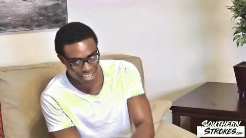 Young athletic ebony guy with glasses smiles in solo gay interview
