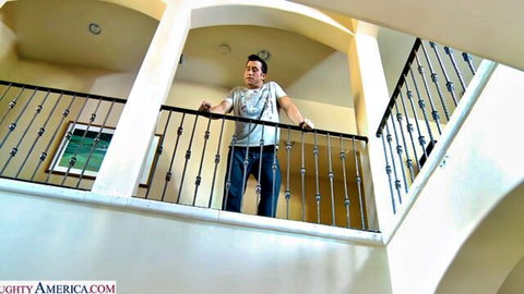 Latino man leaning on balcony railing in luxury home interior