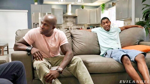 Two muscular black men lounging relaxed on couch in living room before rough action
