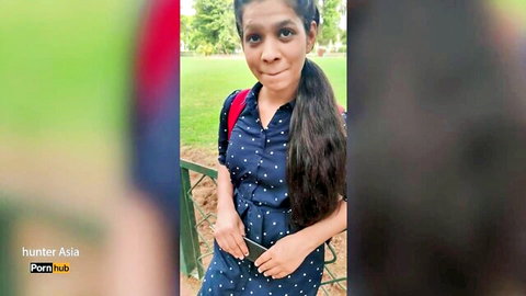 Cute Indian teen brunette with long hair smiling in polka dot dress outdoors at park