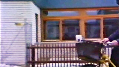 Blurry outdoor scene of person pushing wheelbarrow near house, classic style