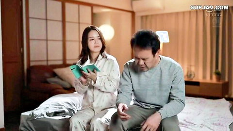 Asian woman with big tits in pajamas sits with man on bed, intimate setup
