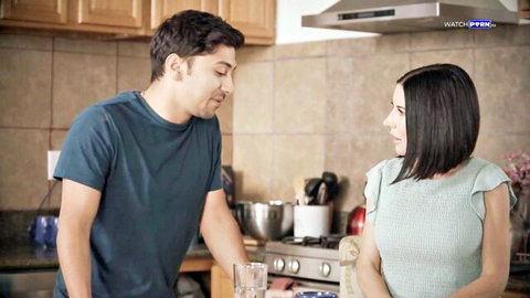 Clothed couple smiling and talking intimately in modern kitchen