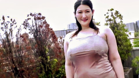 Busty Asian MILF Hidden Desires in revealing pink satin dress, smiling on rooftop