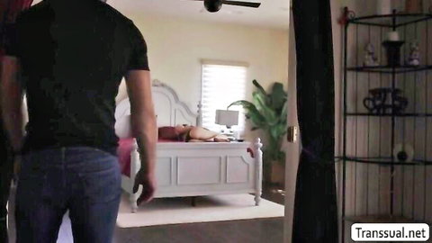 Skinny blonde trans woman lies naked ass-up on bed as clothed man approaches from behind