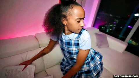 Ebony schoolgirl in plaid uniform skirt teasing seductively on couch with city skyline