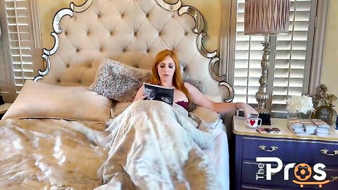Lauren Phillips in red lingerie reading on bed, seductive pose