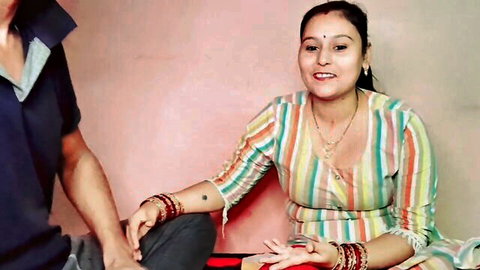 Sexy Indian woman in striped saree smiles as man touches her hand intimately on bed