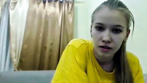 Blonde teen girl with ponytail in yellow shirt on webcam couch