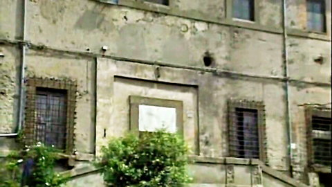 Vintage retro old stucco building facade with barred windows and greenery