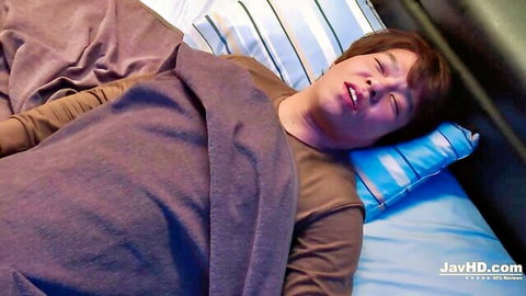Cute Asian guy lying asleep in bed with open mouth on pillows