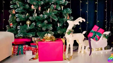 Festive Christmas scene with white reindeer statue pulling sleigh loaded with pink and gold presents beside decorated tree.