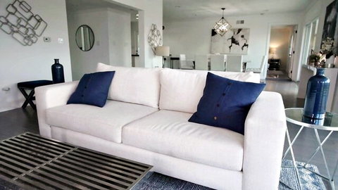 Empty modern living room with plush white sofa and navy pillows ready for naughty fucking