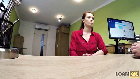 Redhead casting agent with freckles in red blouse interviews man at office desk