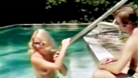 Tanned blonde with tan lines on bare tits grabs pool ladder topless near shirtless guy