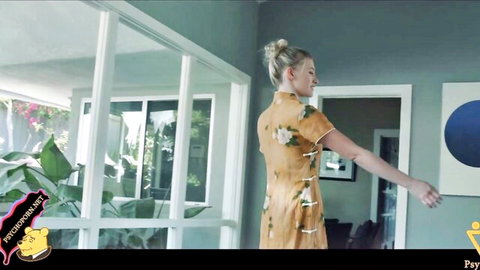 Blonde woman in tight orange floral cheongsam posing seductively from behind in modern home