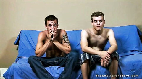 Two shirtless white guys on couch, one tattooed, surprised expressions