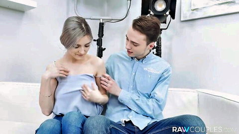 Young couple teasing intimately on couch, grey-haired beauty in blouse