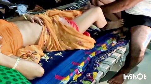 Indian woman in orange saree lies on bed spreading legs as man grabs her bare thighs intimately