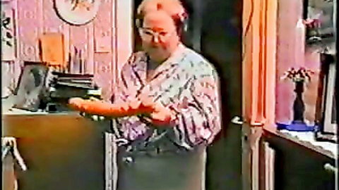 Granny holds massive orange dildo teasingly in front of her pussy in kitchen